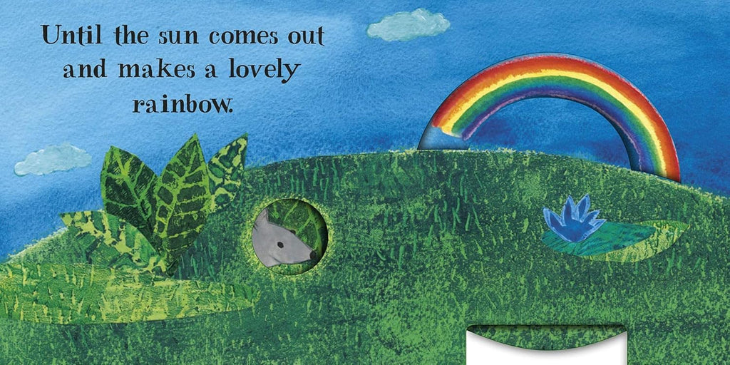 Inner page of 'A Surprise for Tiny Mouse', a turning wheel rainbow above a little grey mouse in the hole of a grassy slope.