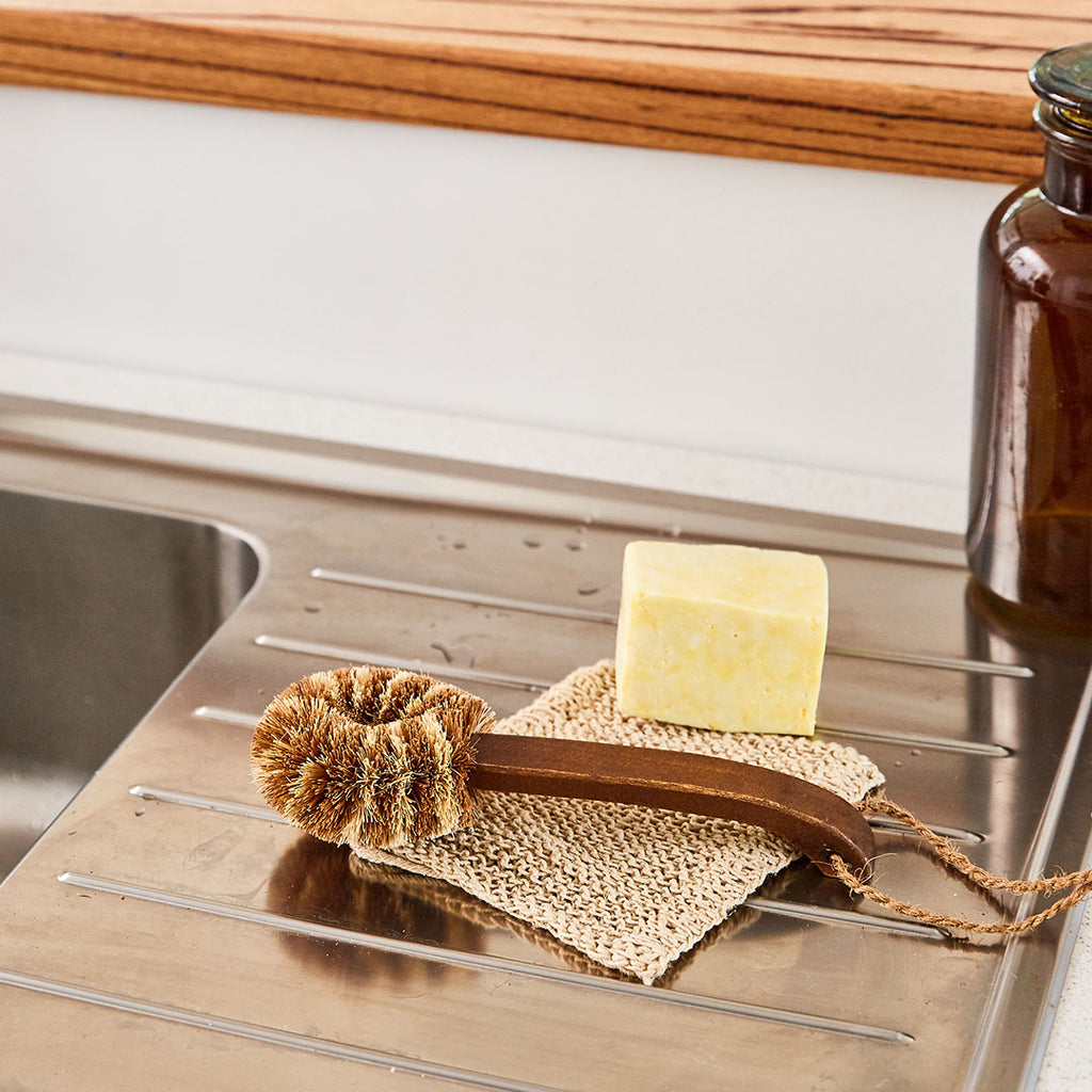 Eco Max Dish Brush with dish soap and dish cloths on a kitchen sink