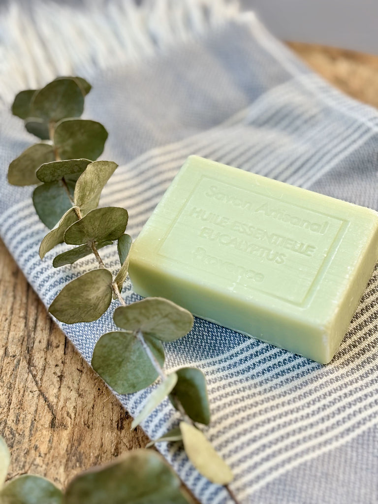 Eucalyptus soap on a blue and white striped fabric with eucalyptus leaves.