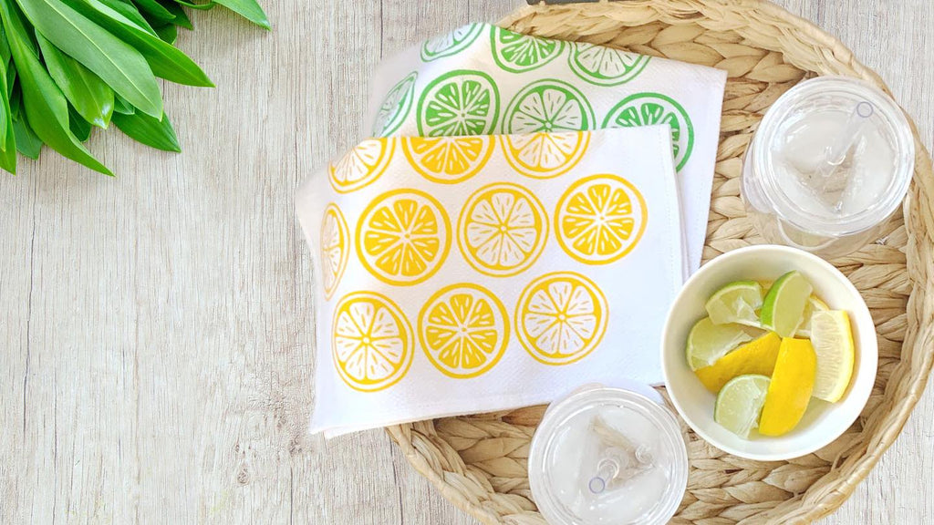 Handecloth Lemons and Limes Reusable Paper Towel with water and lemon lime slices on woven tray 