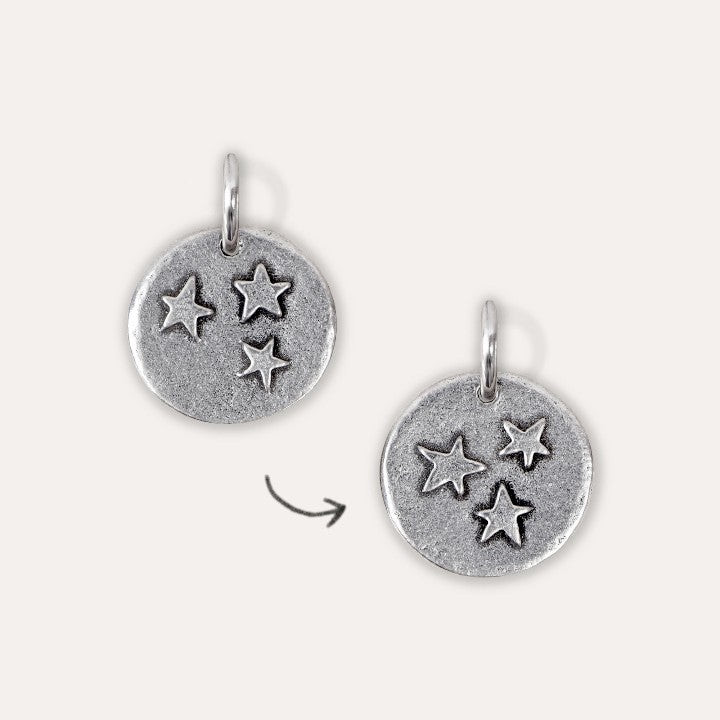 A round pewter charm with an embossed stars print design and a loop at the top.