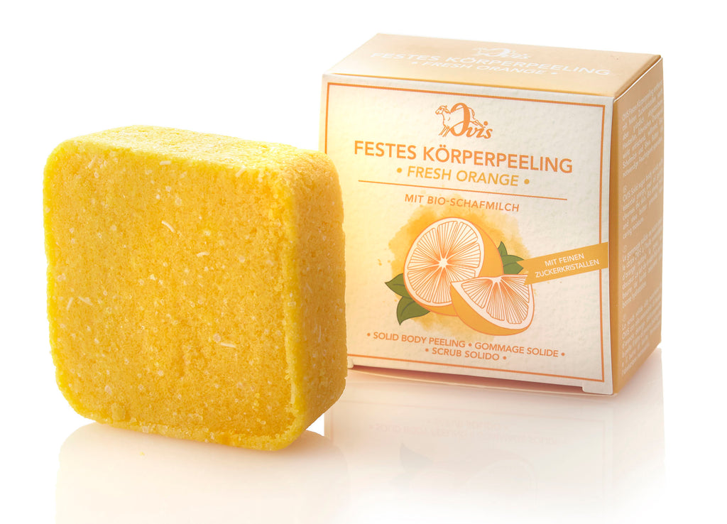 Solid orange body scrub and a matching orange-themed box featuring orange slices illustration.