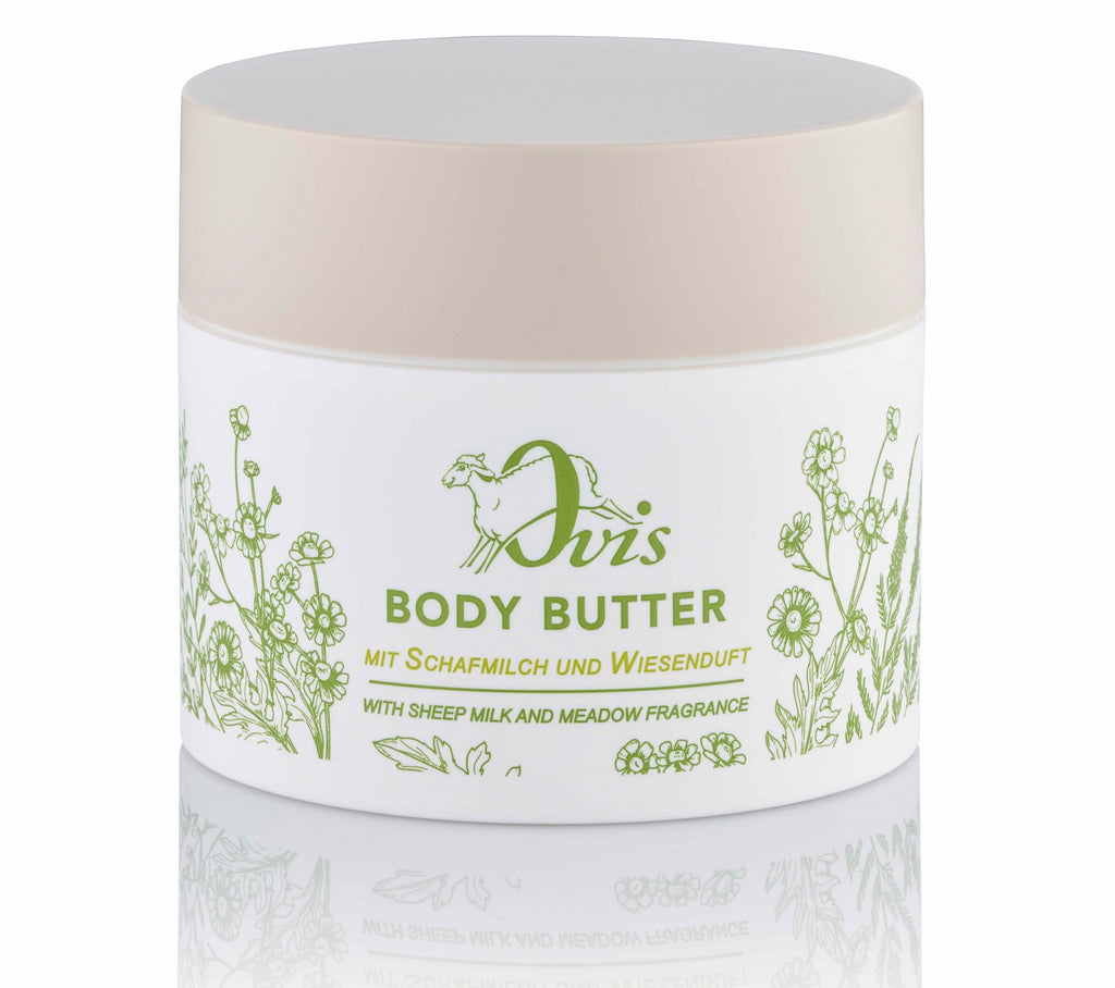 A white container of body butter with a beige lid and green floral designs.