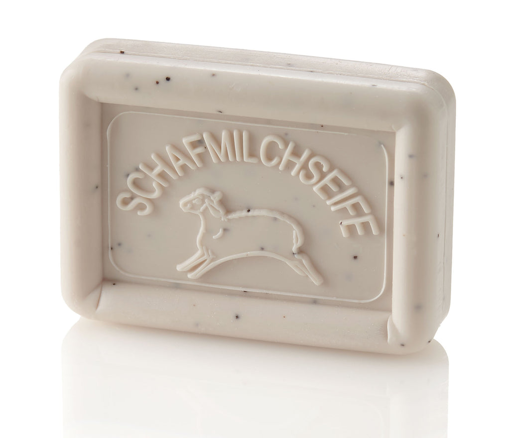 Rectangular beige soap bar with dark specks, embossed with "SCHAFMILCHSEIFE" and a sheep outline.