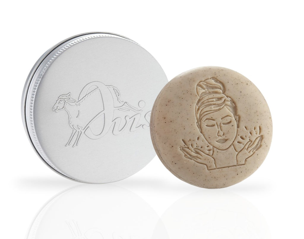 Round beige solid facial mask with embossed face design, and a silver travel tin with sheep illustration and "Ovis" text.