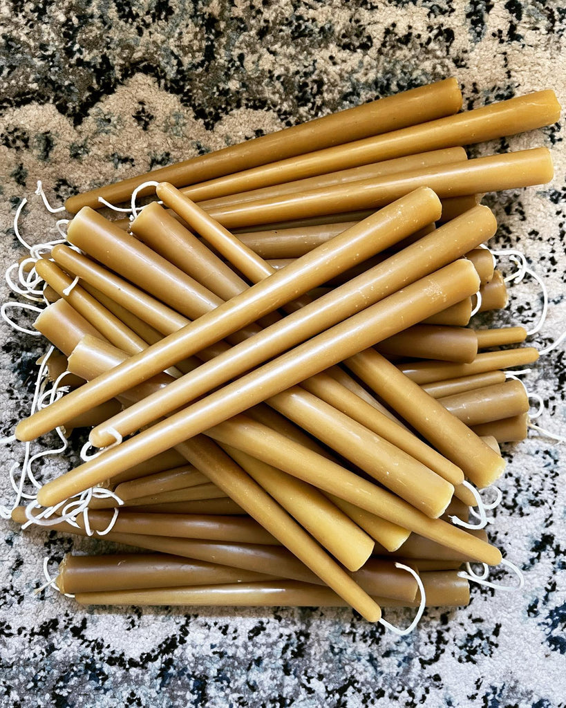A pile of "Pine Barrens Post" taper candles with white wicks.
