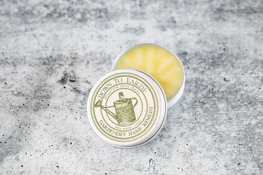 Open tin of "Gardener's Hand Remedy" balm with a watering can illustration on the lid.
