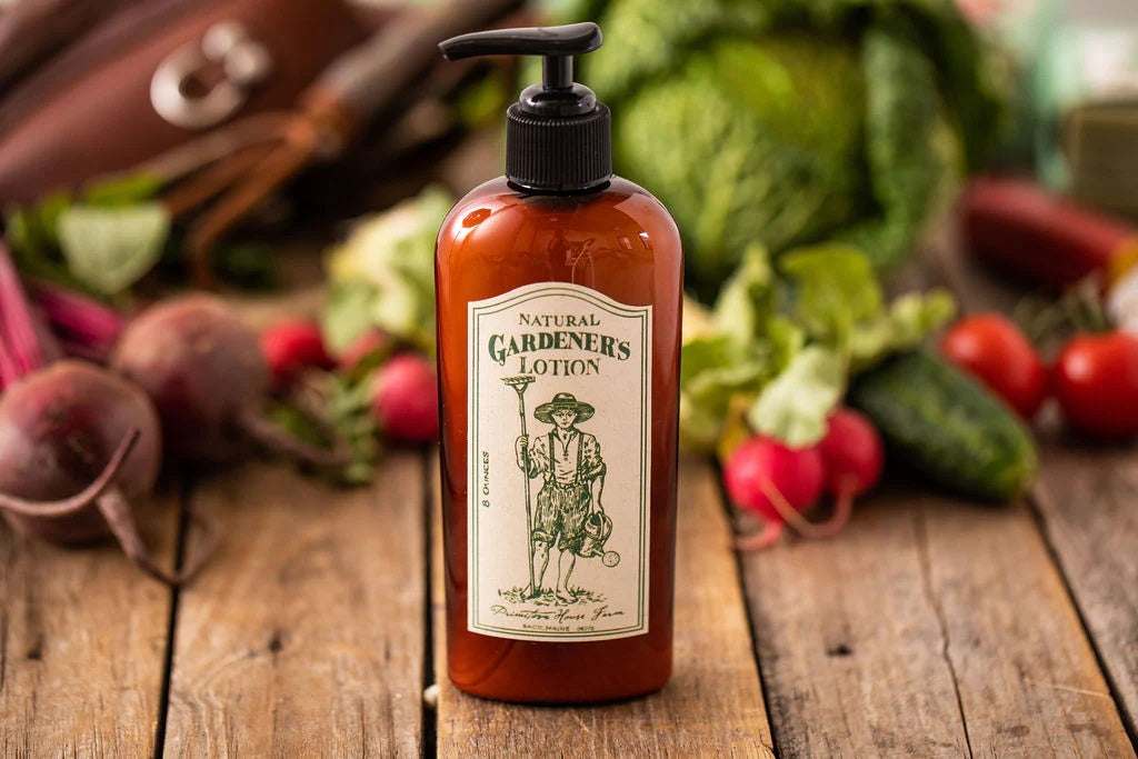 A brown bottle of "Natural Gardener's Lotion" with a black pump with vegetables on a wooden surface.