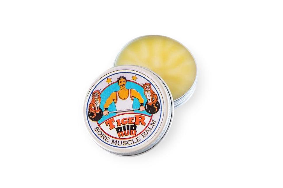 Open tin of "Tiger Sore Muscle Balm" with an illustrated lid showing a muscular man with tigers.