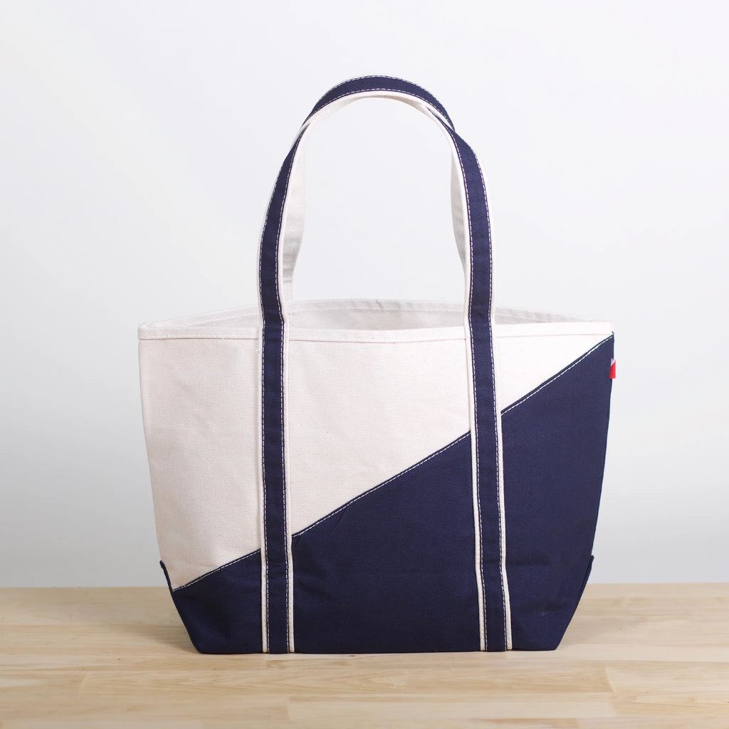 ShoreBags Contemporary Canvas Tote bag with off-white and navy blue diagonal design and navy blue handles on a light wooden surface.