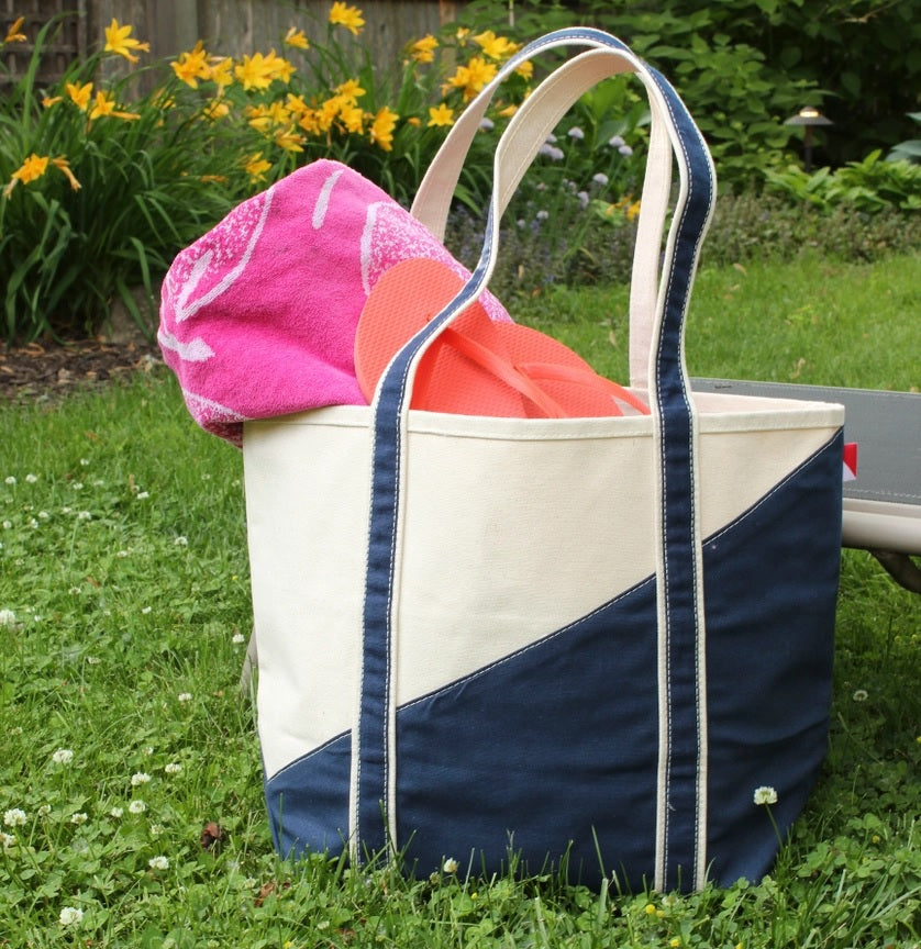 ShoreBags Contemporary Canvas Tote bag with a pink towel and orange flip-flops on grass, surrounded by yellow flowers.