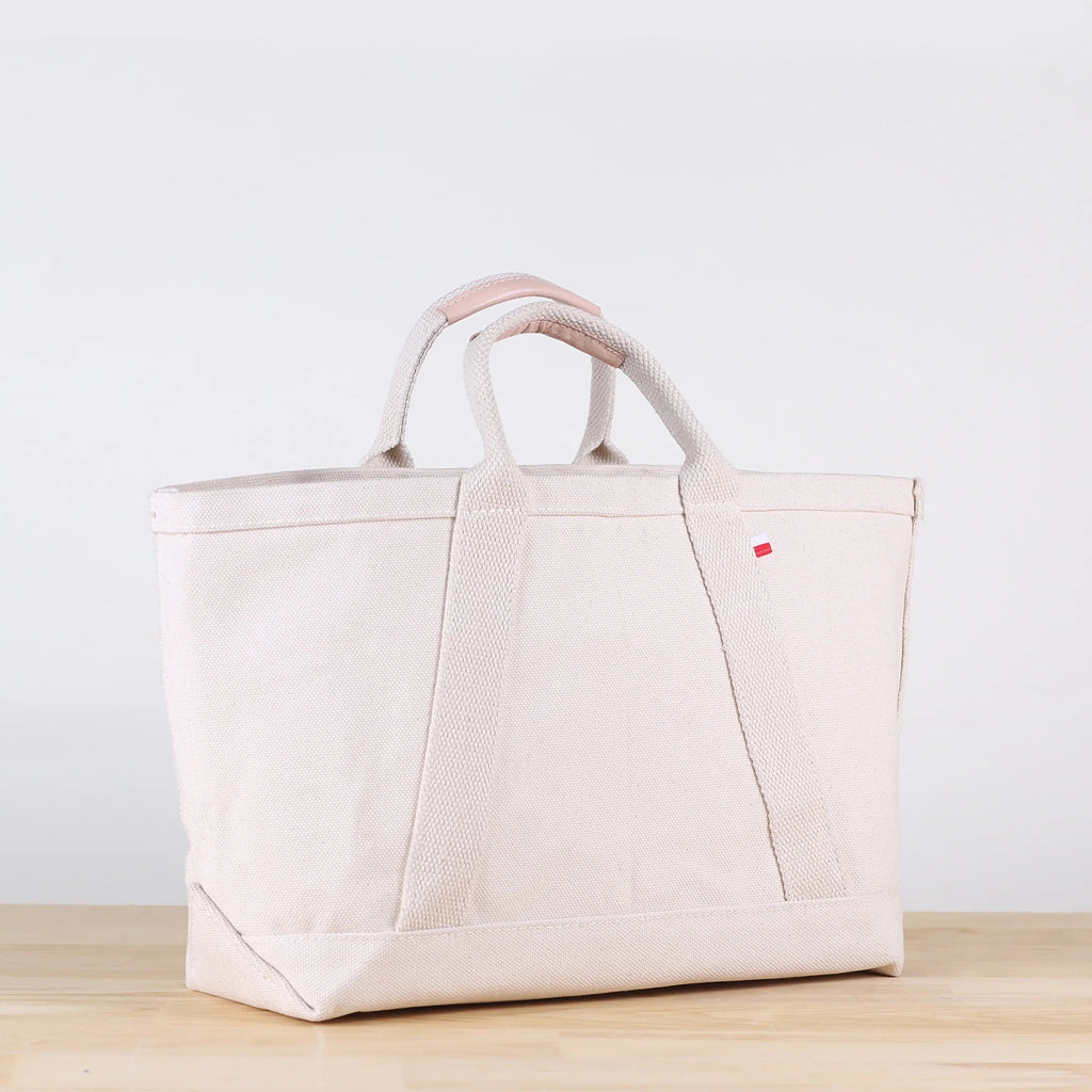 ShoreBags Utility Heavyweight Canvas Tote bag with handles, featuring a red tag on a light wooden surface.