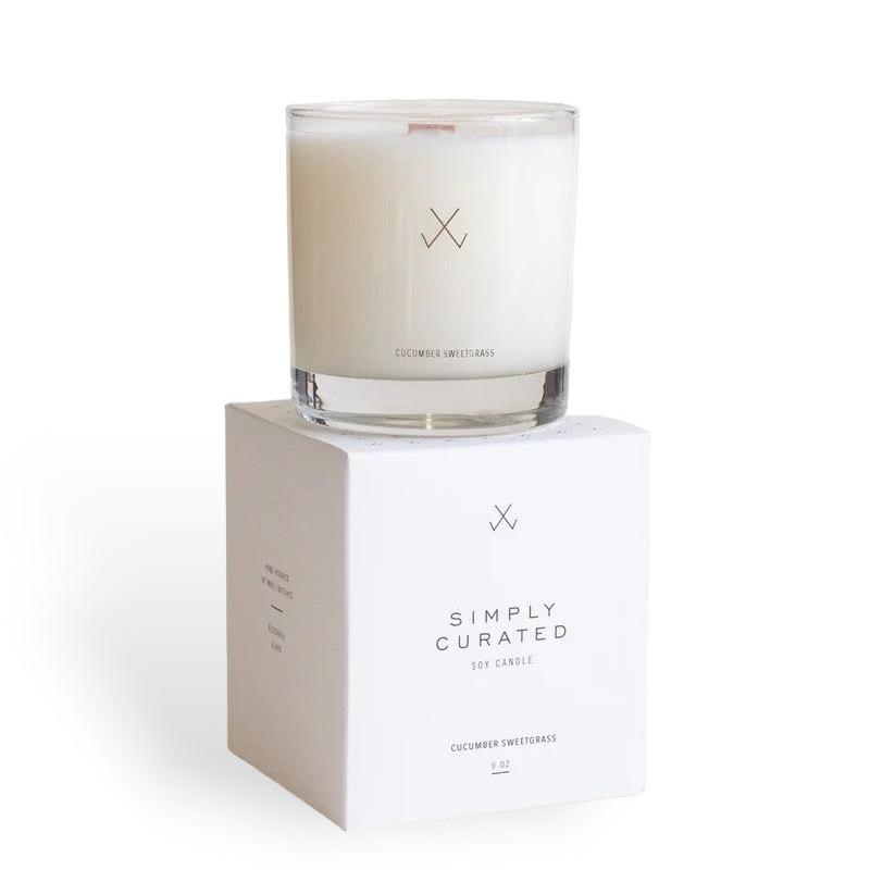A Simply Curated cucumber sweetgrass soy candle on its white packaging box with minimalistic branding logo.