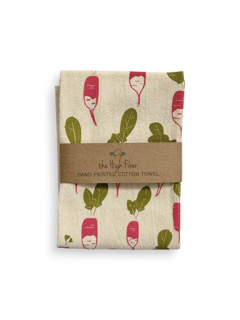 A folded beige tea towel with red radish and green leaves patterns and a brown paper band with brand name "the High Fiber" and logo.